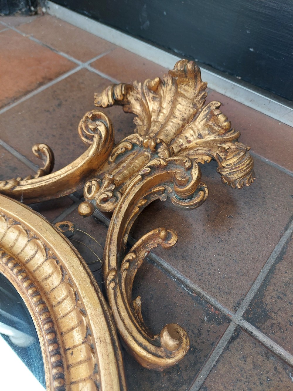 An early 19th-century oval giltwood wall mirror featuring a carved acanthus cresting and matching bottom pendant. View VI