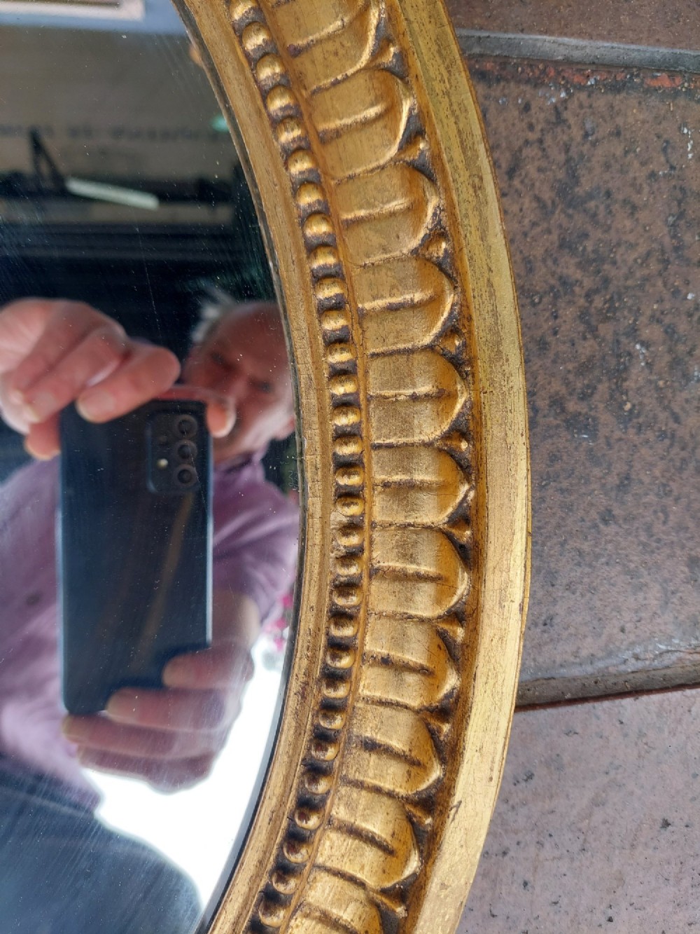 An early 19th-century oval giltwood wall mirror featuring a carved acanthus cresting and matching bottom pendant. View VII