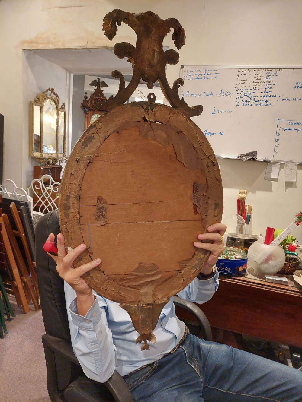 An early 19th-century oval giltwood wall mirror featuring a carved acanthus cresting and matching bottom pendant. View VIII