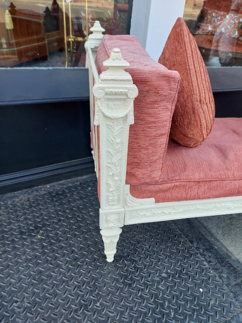 A white painted late Victorian cast iron daybed with relief mouldings, finials, fluted legs, and pink cushion upholstery. View VIII
