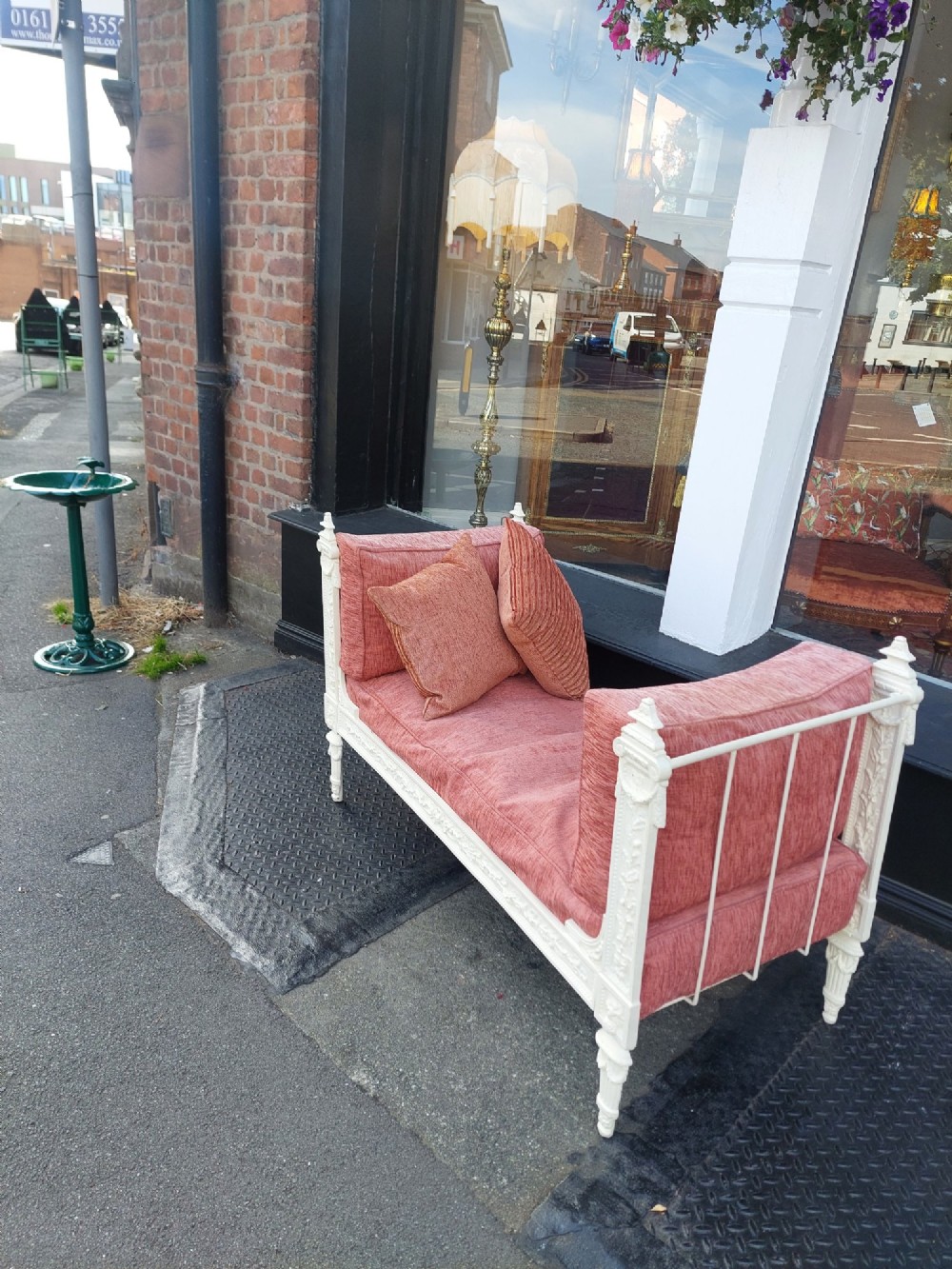 A white painted late Victorian cast iron daybed with relief mouldings, finials, fluted legs, and pink cushion upholstery. View X
