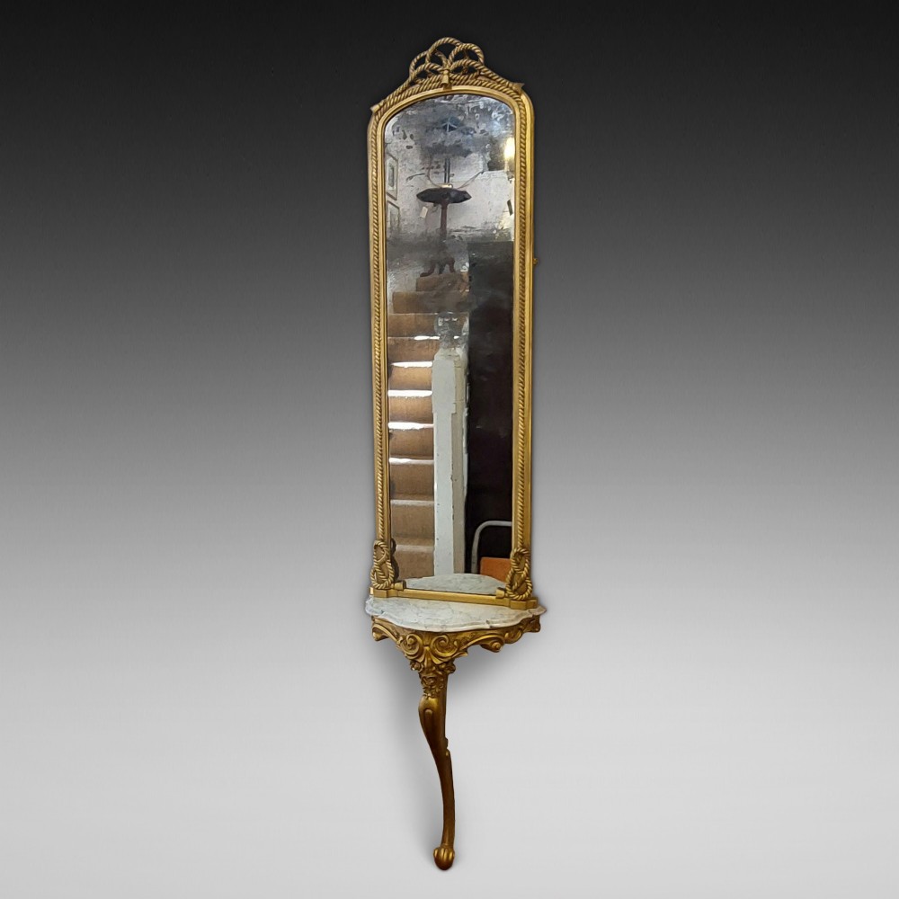 A tall late 19th-century French gilt gesso pier mirror featuring a rope-twist border and top ribbon motif, mounted above a small marble-topped single-leg console.