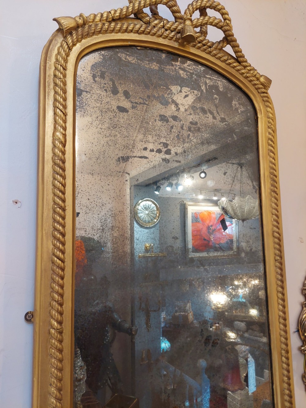 A tall late 19th-century French gilt gesso pier mirror featuring a rope-twist border and top ribbon motif, mounted above a small marble-topped single-leg console. View V