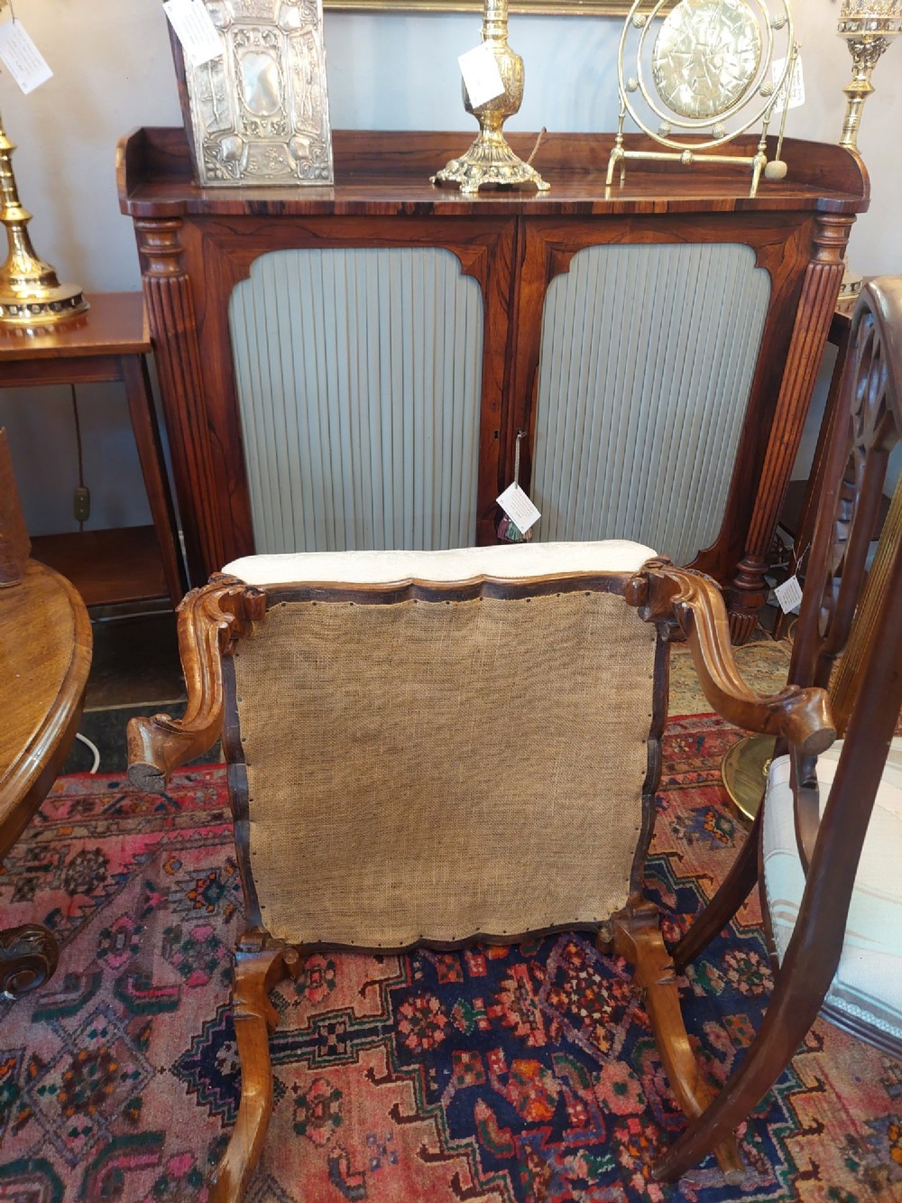 A Victorian walnut stool featuring carved cabriole legs, a serpentine apron, and a cream button-tufted upholstered top. View VI