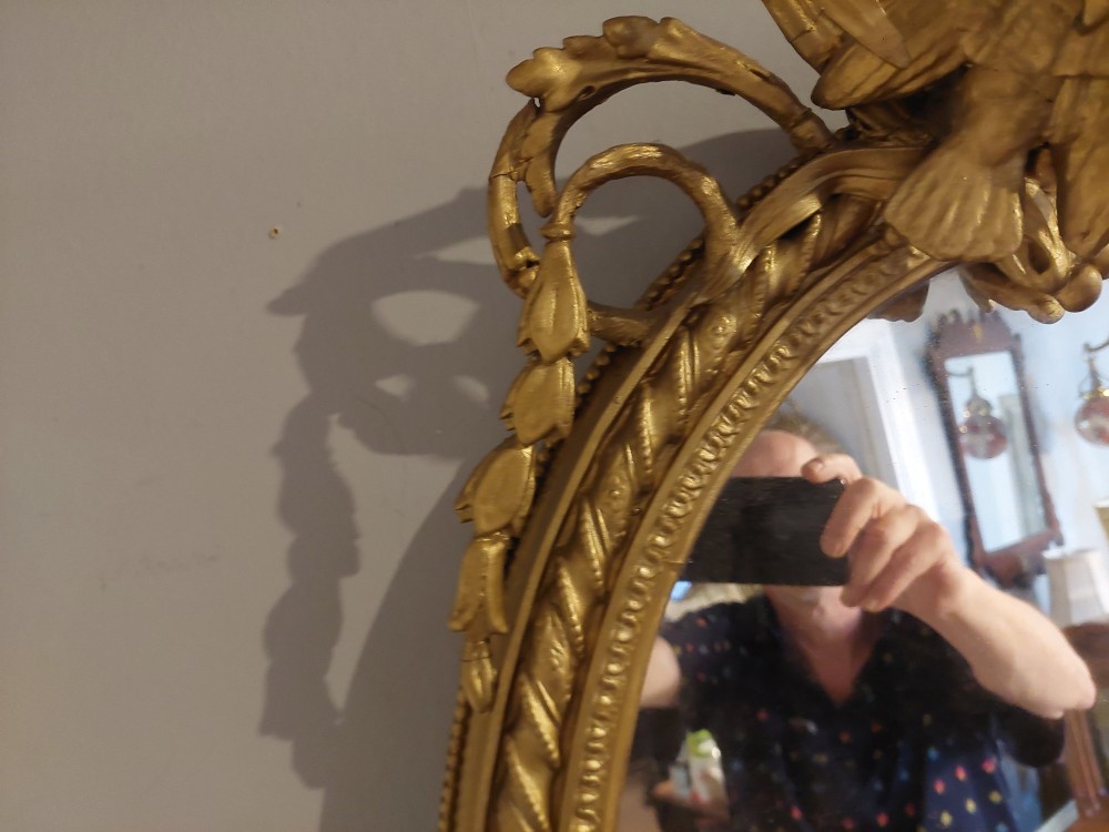 A pair of late nineteenth-century oval giltwood girandole mirrors featuring ribbon crests and twin candle arms at the base. View VI