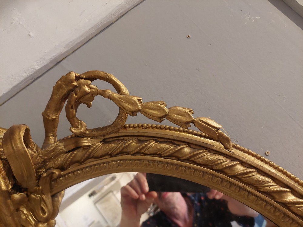 A pair of late nineteenth-century oval giltwood girandole mirrors featuring ribbon crests and twin candle arms at the base. View VII