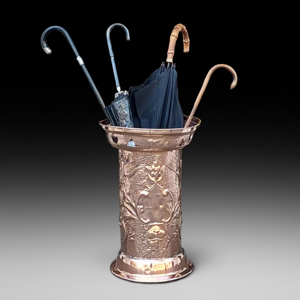 Cylindrical Art Nouveau copper umbrella stand with embossed organic relief motifs, a flared top rim, and a weighted base. View IX