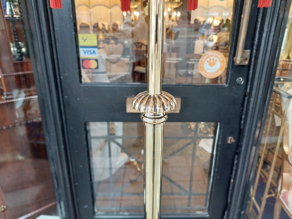 A Victorian brass standard floor lamp featuring a tripod claw-foot base, decorative mid-stem mounts, and a cream domed fabric shade trimmed with fringe and red tassels. View VIII