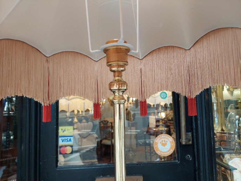 A Victorian brass standard floor lamp featuring a tripod claw-foot base, decorative mid-stem mounts, and a cream domed fabric shade trimmed with fringe and red tassels. View IX
