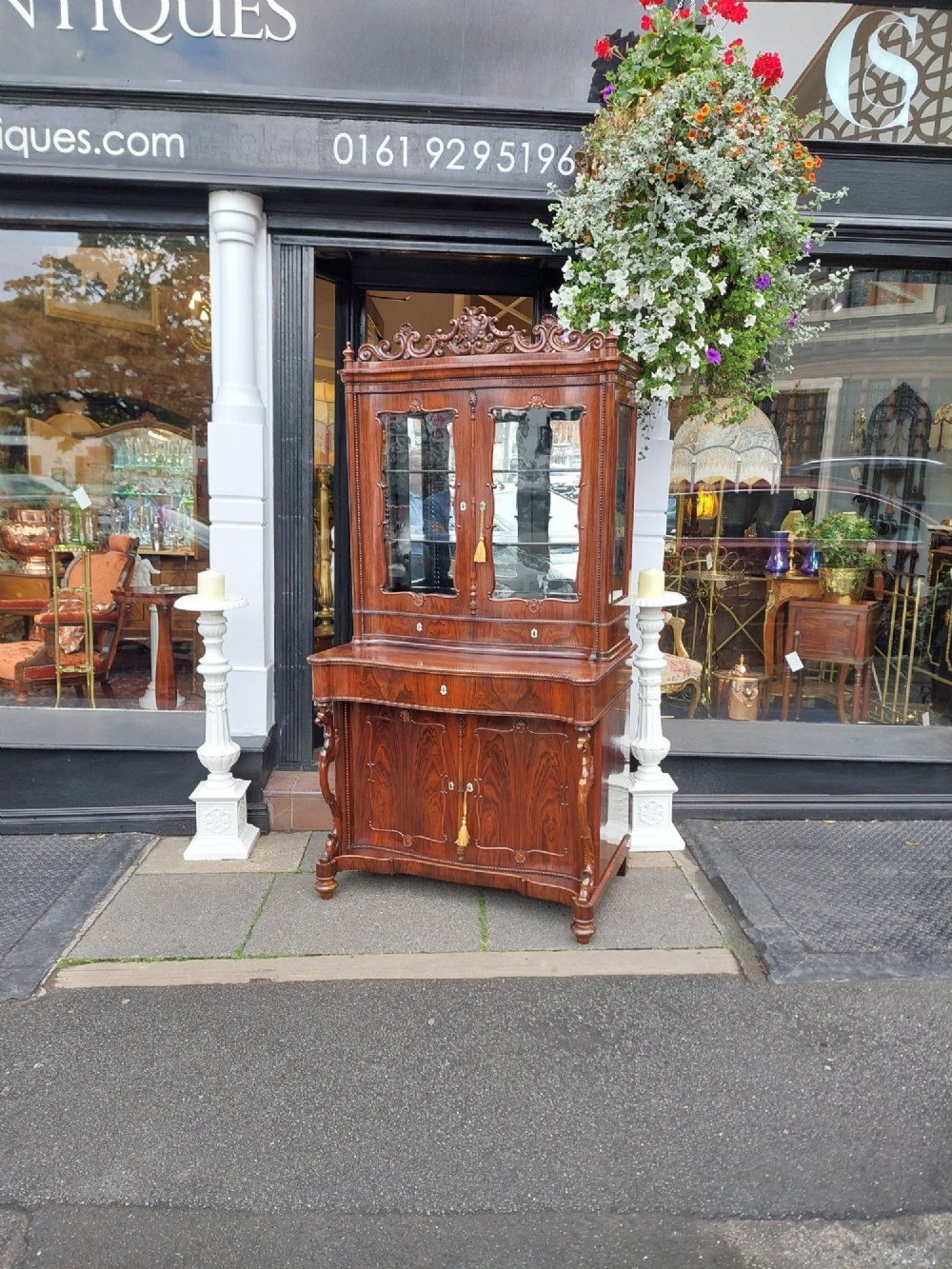 A two-tier Biedermeier rosewood display cabinet featuring a glazed upper section with a carved cresting above a two-door cupboard base. View II