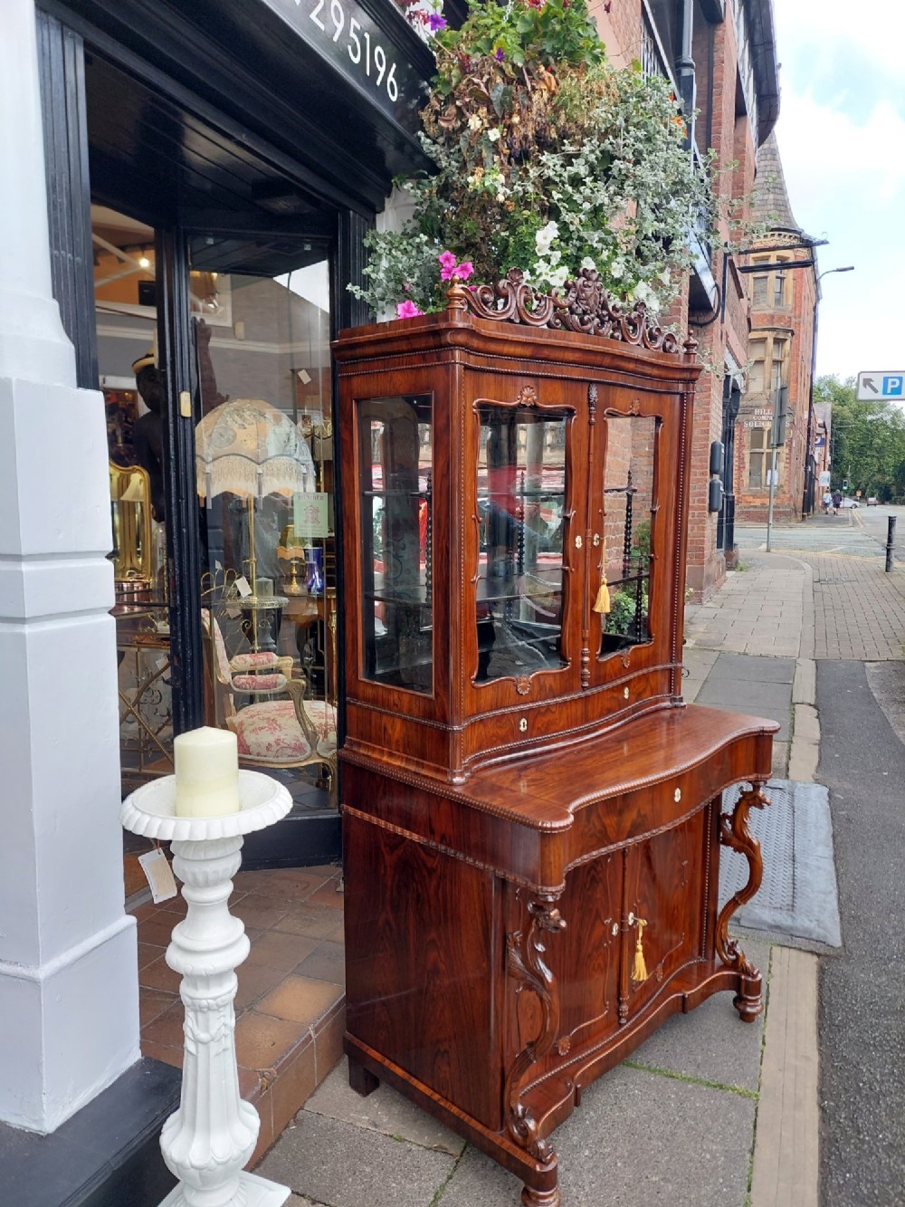 A two-tier Biedermeier rosewood display cabinet featuring a glazed upper section with a carved cresting above a two-door cupboard base. View XI