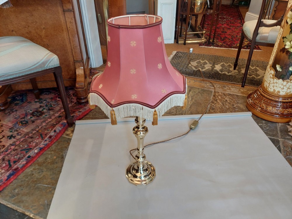 A Victorian turned brass candlestick table lamp featuring a rose pink embroidered lampshade with fringe and tassel trim. View II