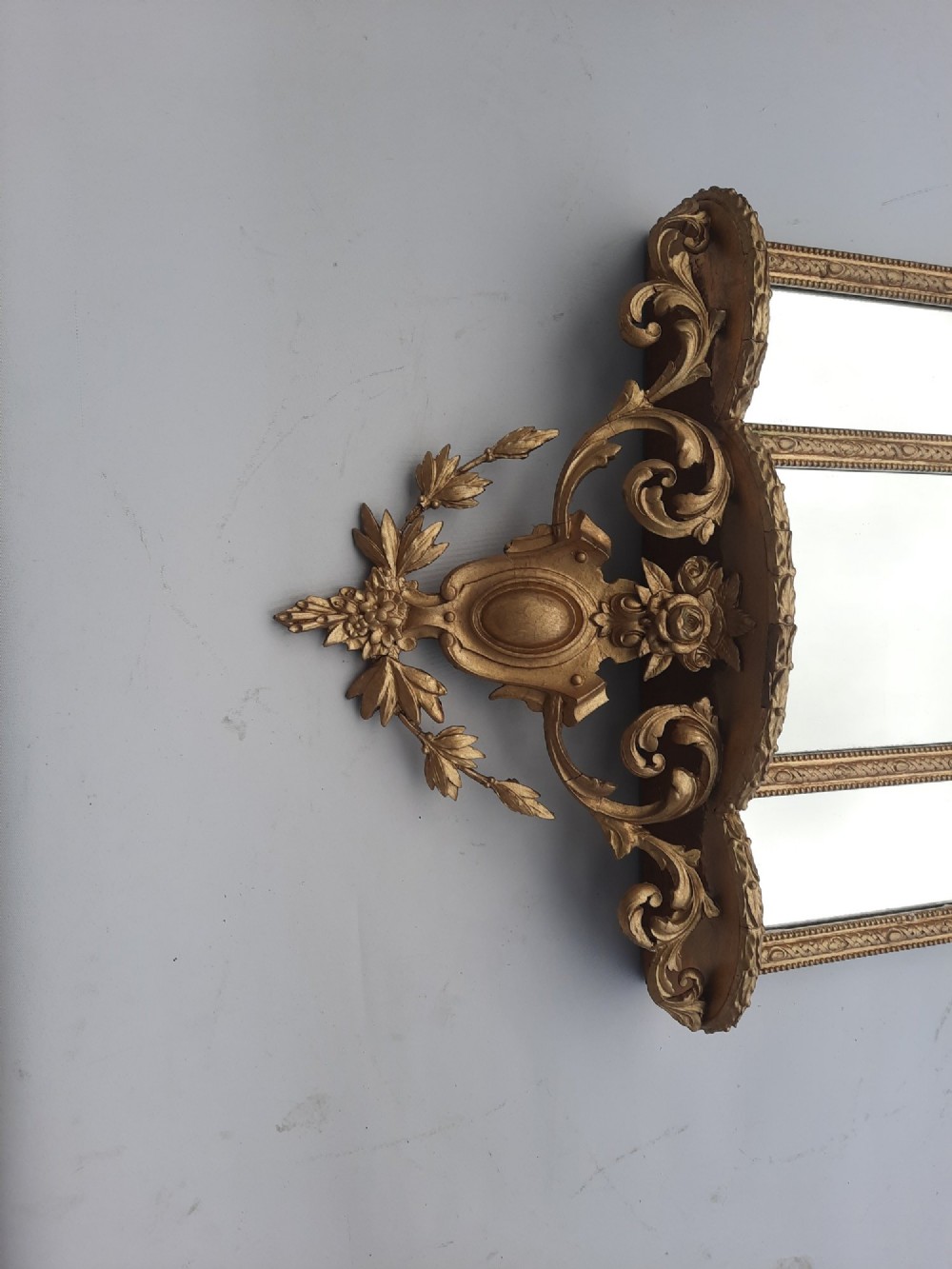 A late nineteenth-century three-panel gilt wall mirror featuring an arched central plate, intricate carved floral cresting, and an integrated base shelf. View III
