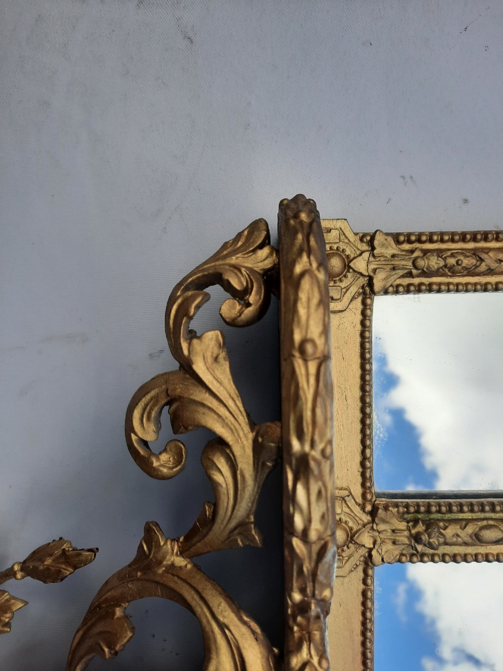 A late nineteenth-century three-panel gilt wall mirror featuring an arched central plate, intricate carved floral cresting, and an integrated base shelf. View VIII