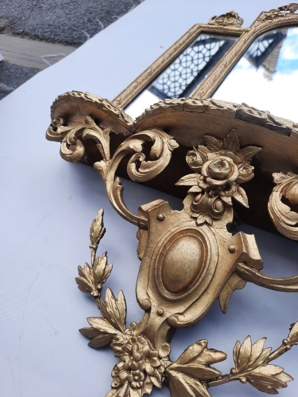 A late nineteenth-century three-panel gilt wall mirror featuring an arched central plate, intricate carved floral cresting, and an integrated base shelf. View IX
