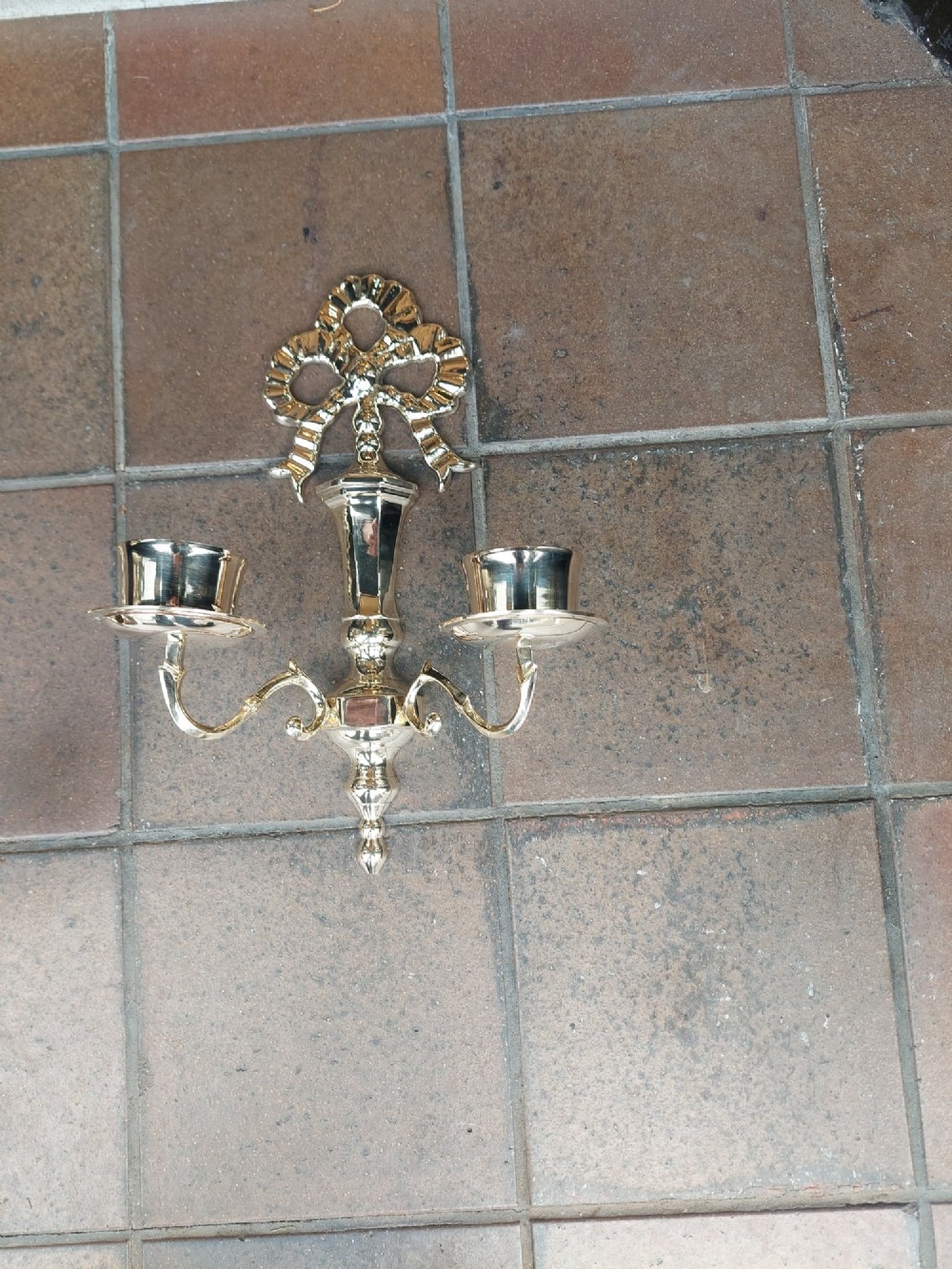 A pair of polished brass double-arm wall sconces featuring ribbon bow top motifs, urn-shaped central stems, and scrolling candle branches. View III