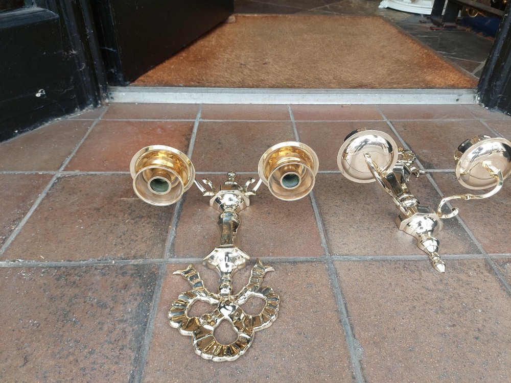 A pair of polished brass double-arm wall sconces featuring ribbon bow top motifs, urn-shaped central stems, and scrolling candle branches. View VI