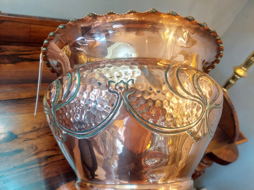 An Edwardian Art Nouveau copper planter featuring a hand-hammered texture, embossed leaf motifs, and a crimped rim. View VI