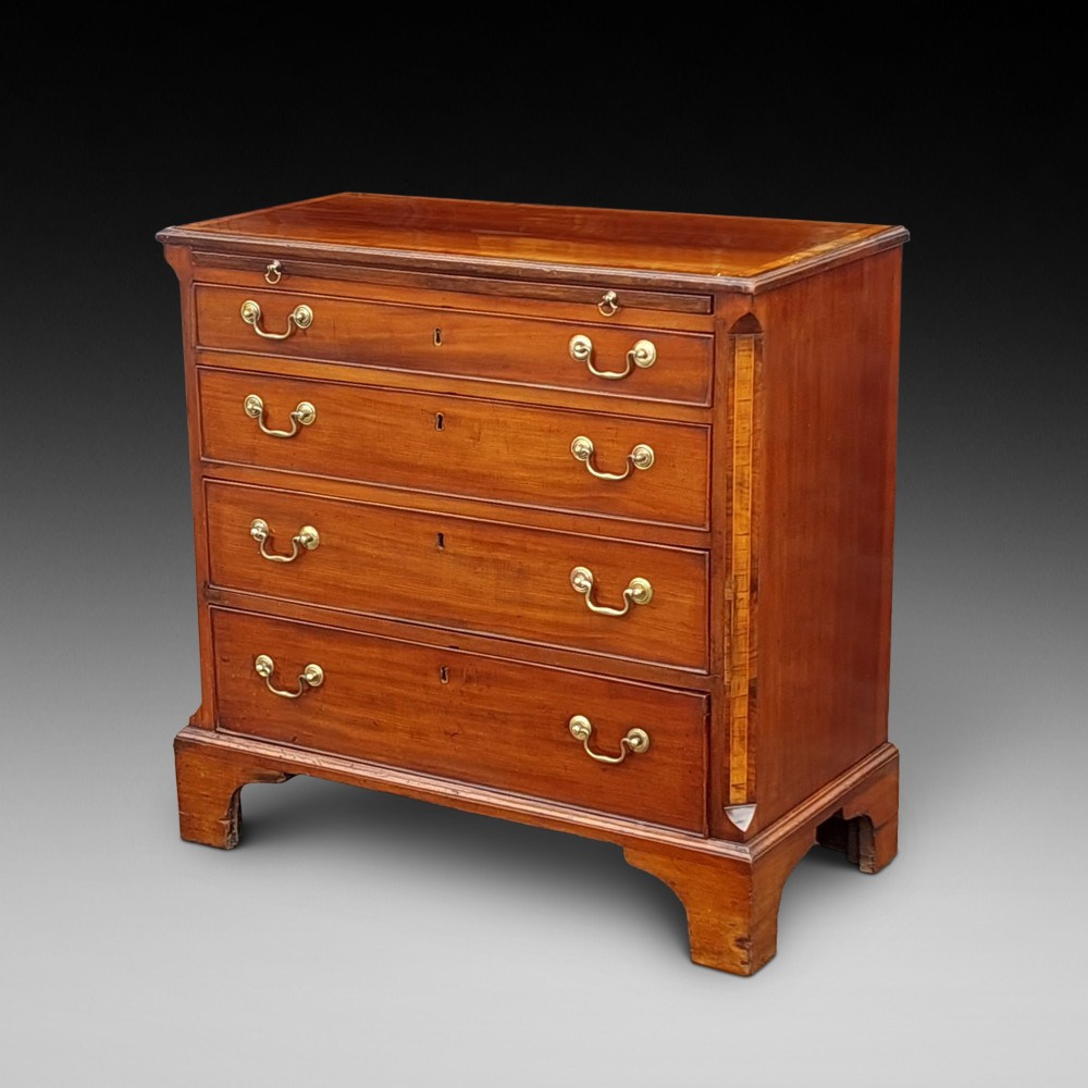 A George III mahogany bachelors chest featuring four graduated drawers, brass swan-neck handles, an upper pull-out brushing slide, and classic bracket feet.