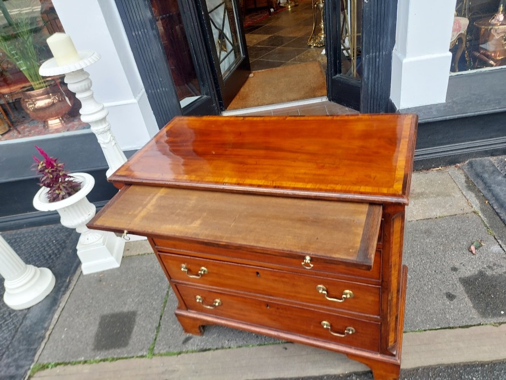 A George III mahogany bachelors chest featuring four graduated drawers, brass swan-neck handles, an upper pull-out brushing slide, and classic bracket feet. View III