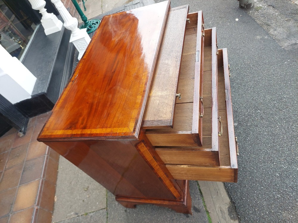 A George III mahogany bachelors chest featuring four graduated drawers, brass swan-neck handles, an upper pull-out brushing slide, and classic bracket feet. View IV