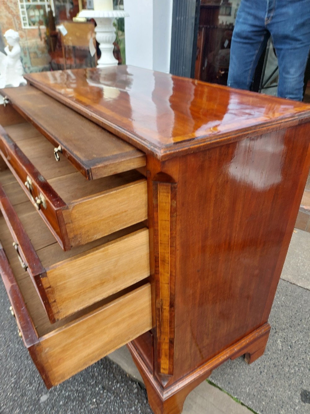 A George III mahogany bachelors chest featuring four graduated drawers, brass swan-neck handles, an upper pull-out brushing slide, and classic bracket feet. View V
