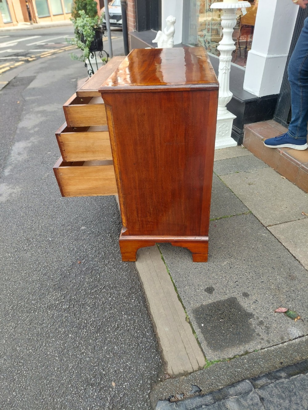 A George III mahogany bachelors chest featuring four graduated drawers, brass swan-neck handles, an upper pull-out brushing slide, and classic bracket feet. View VI