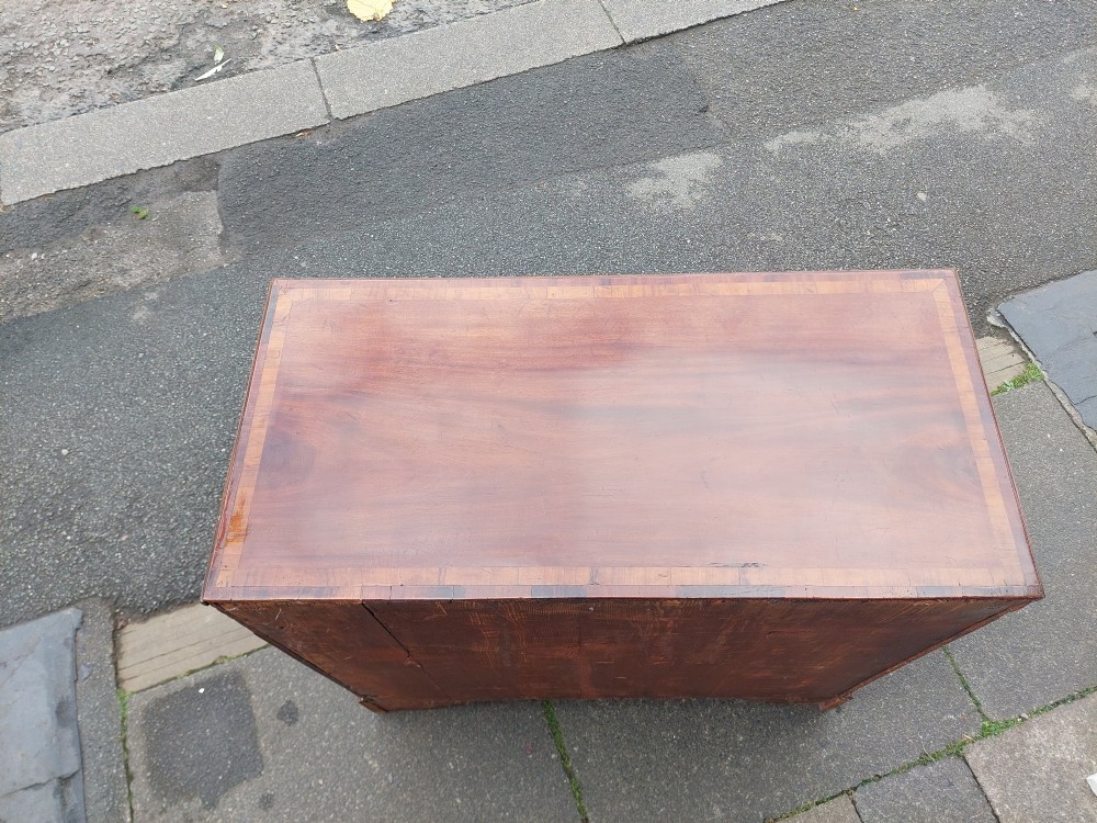 A George III mahogany bachelors chest featuring four graduated drawers, brass swan-neck handles, an upper pull-out brushing slide, and classic bracket feet. View X