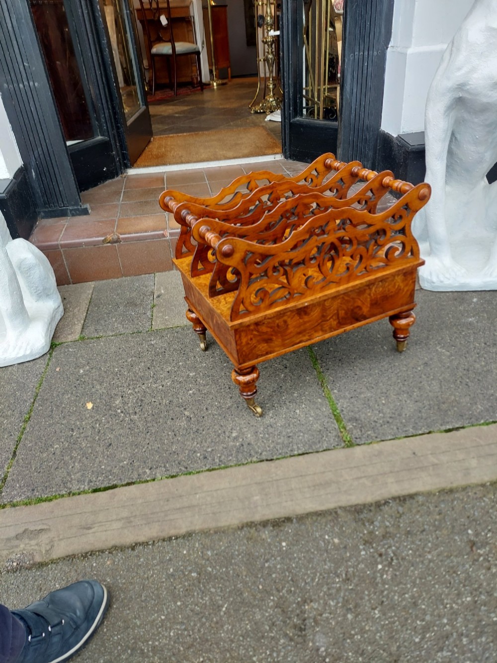 A High Victorian burr walnut Canterbury featuring four open compartments with fretwork dividers above a single drawer with turned legs on brass castors. View IX
