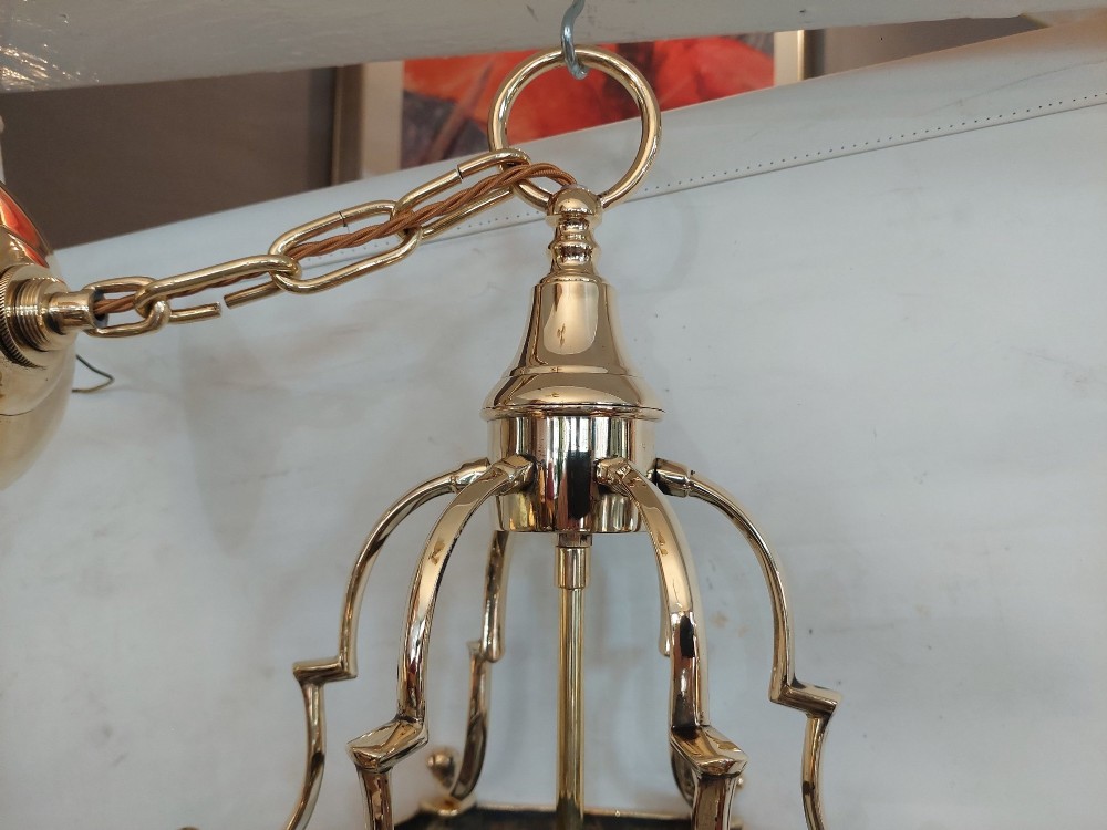 A hexagonal polished brass ceiling lantern with clear glass side panels, scrolled top canopy, and turned bottom finials. View V