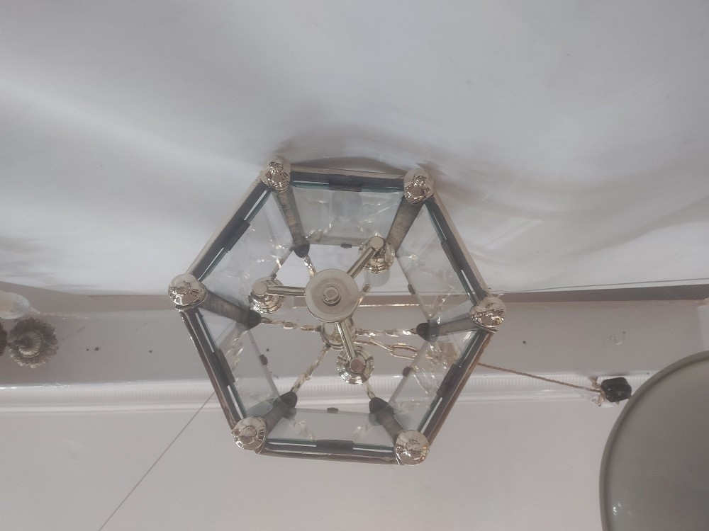 A hexagonal polished brass ceiling lantern with clear glass side panels, scrolled top canopy, and turned bottom finials. View VII