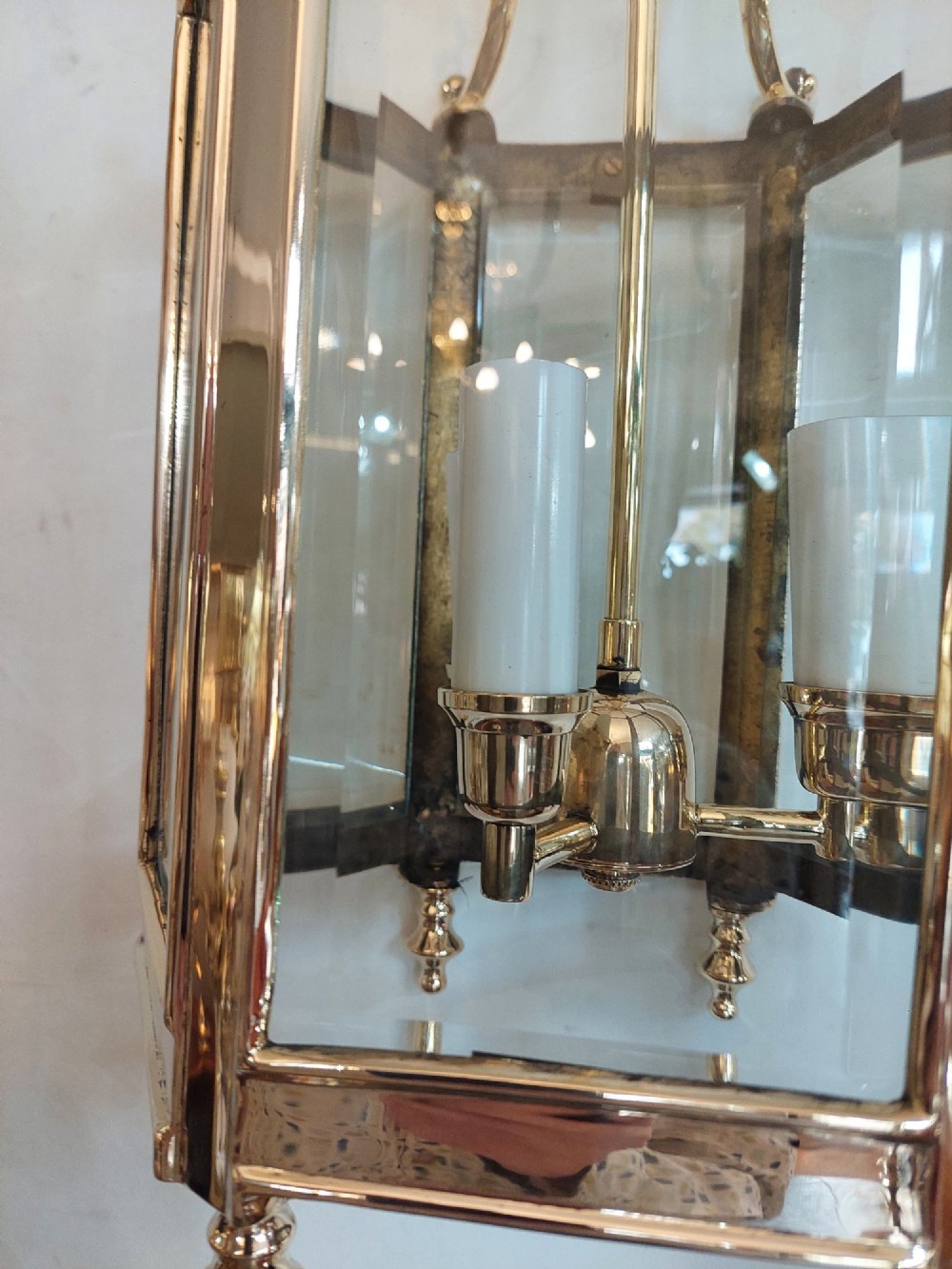 A hexagonal polished brass ceiling lantern with clear glass side panels, scrolled top canopy, and turned bottom finials. View X