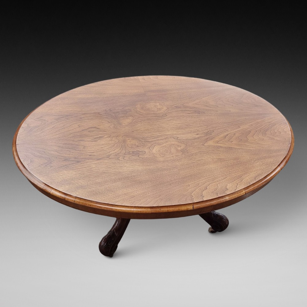 A low oval Victorian coffee table crafted from faded rosewood with a highly figured grain top and a carved pedestal base.