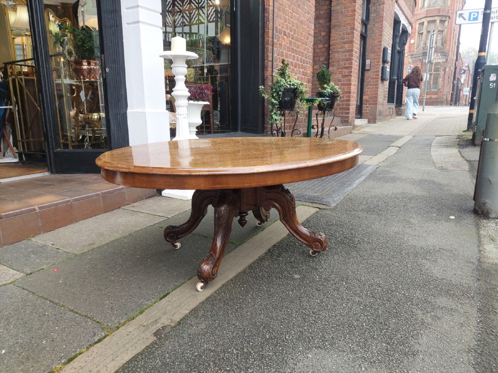 A low oval Victorian coffee table crafted from faded rosewood with a highly figured grain top and a carved pedestal base. View III