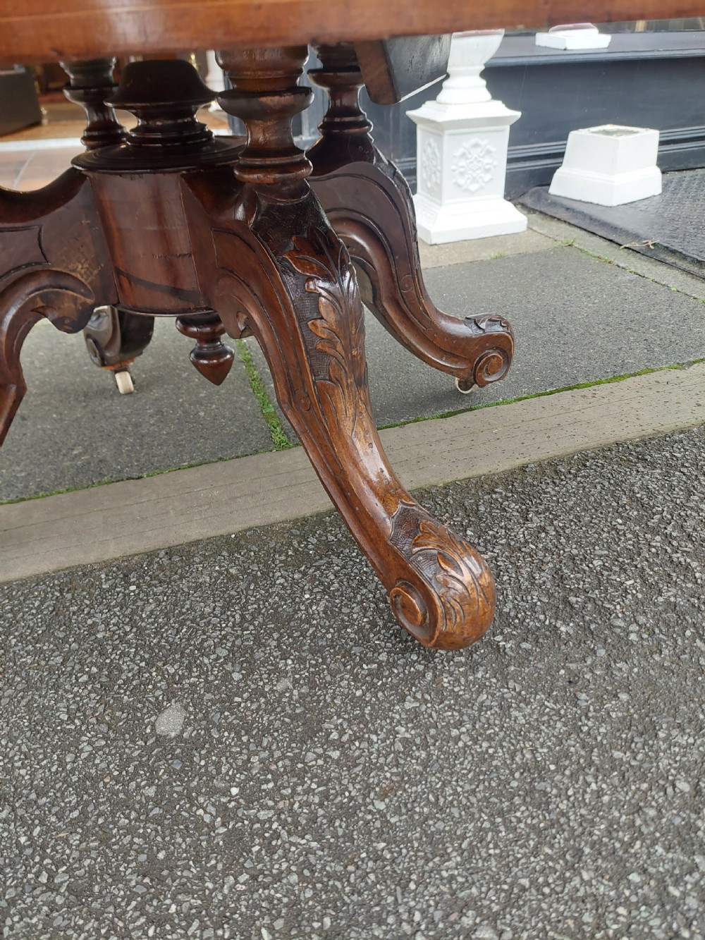 A low oval Victorian coffee table crafted from faded rosewood with a highly figured grain top and a carved pedestal base. View IV
