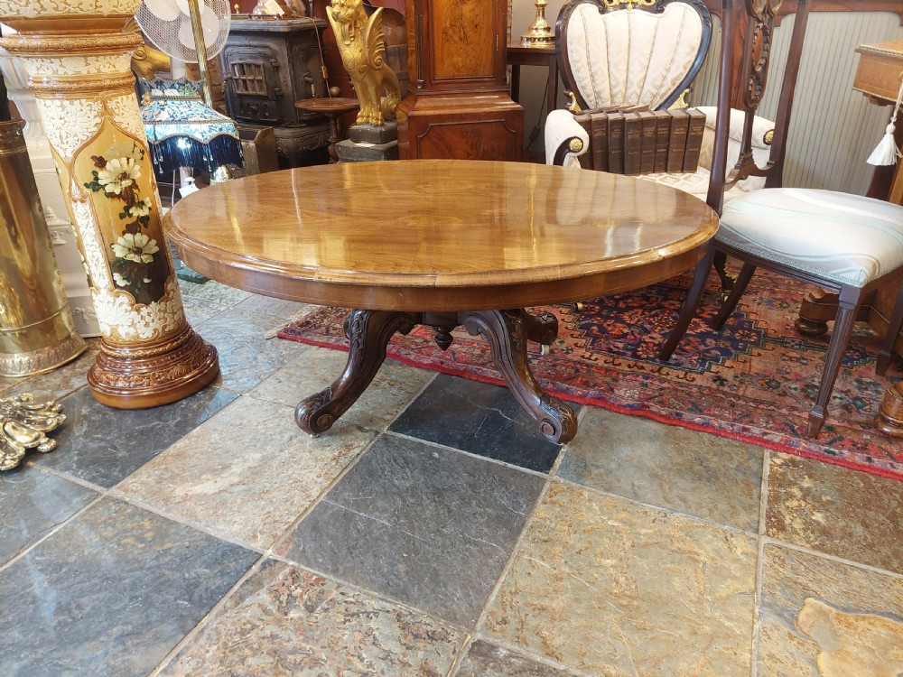 A low oval Victorian coffee table crafted from faded rosewood with a highly figured grain top and a carved pedestal base. View VI