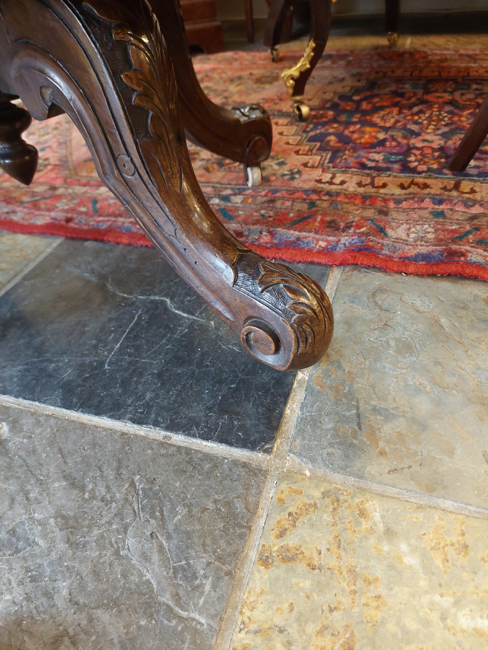 A low oval Victorian coffee table crafted from faded rosewood with a highly figured grain top and a carved pedestal base. View VII