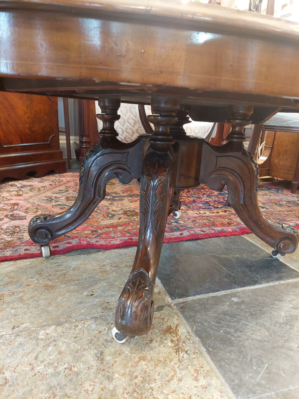 A low oval Victorian coffee table crafted from faded rosewood with a highly figured grain top and a carved pedestal base. View IX