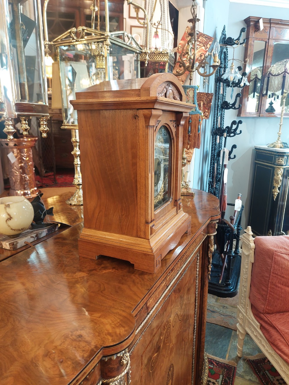 An antique oak mantel clock featuring carved columns, an arched brass dial with silvered numerals, and two small subsidiary dials. View II