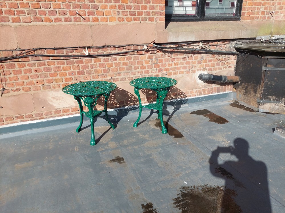 A pair of circular green painted cast iron garden tables featuring pierced foliate tops, mask-adorned legs, and a lower triangular stretcher shelf. View II