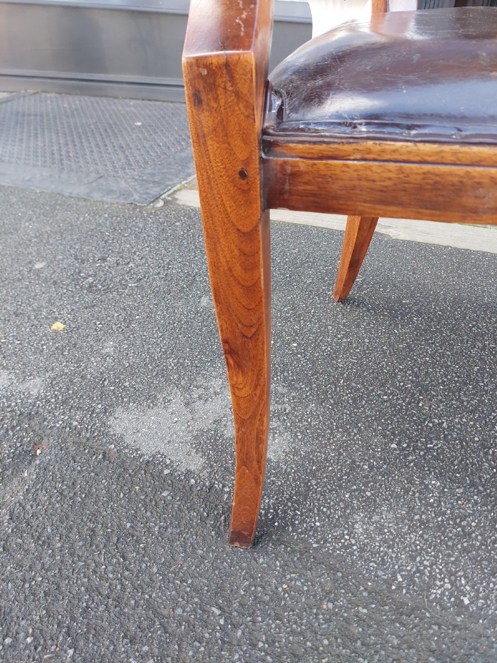 A 19th-century French elm desk chair featuring a curved backrest, sweeping armrests, and a dark leather upholstered seat. View VI
