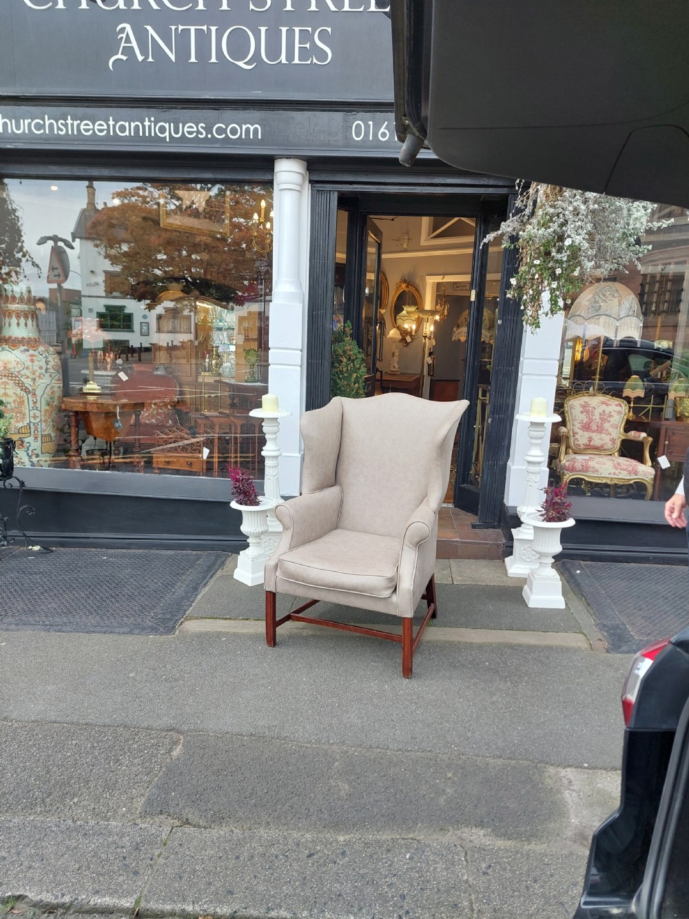 A Victorian wingback armchair upholstered in off-white leather with scrolled arms and dark mahogany legs connected by stretchers. View II