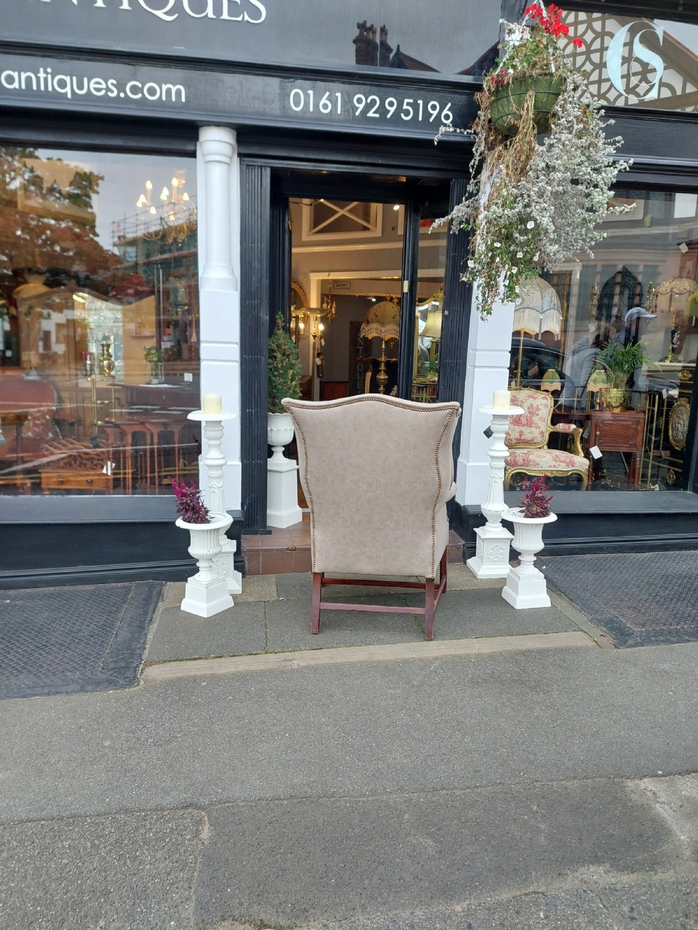 A Victorian wingback armchair upholstered in off-white leather with scrolled arms and dark mahogany legs connected by stretchers. View VI