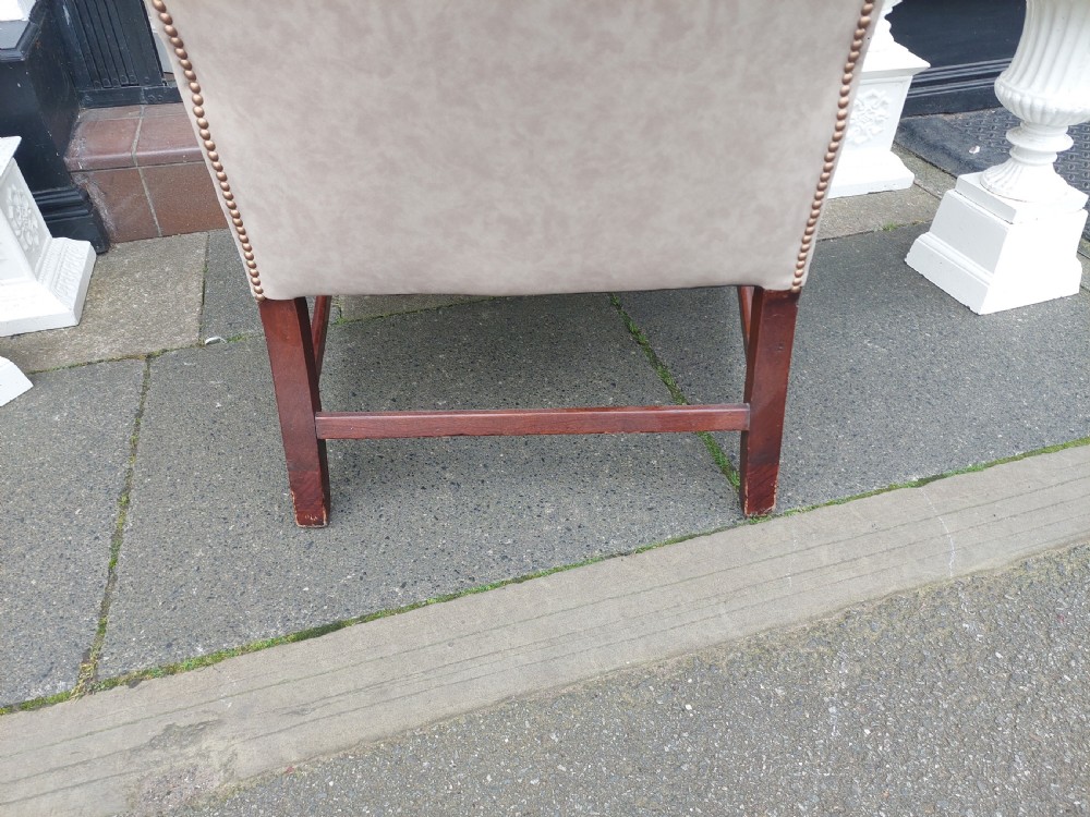 A Victorian wingback armchair upholstered in off-white leather with scrolled arms and dark mahogany legs connected by stretchers. View VII