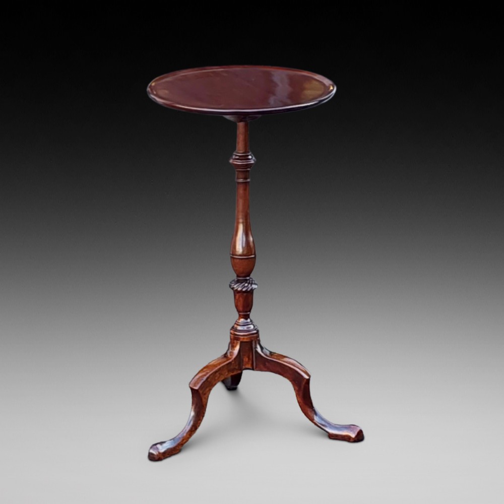 An Edwardian mahogany wine table featuring a polished circular top, turned central column, and three cabriole tripod legs.