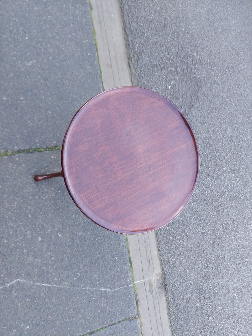 An Edwardian mahogany wine table featuring a polished circular top, turned central column, and three cabriole tripod legs. View II