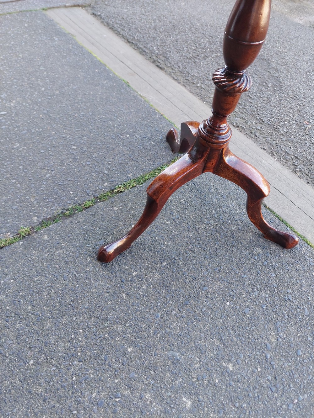 An Edwardian mahogany wine table featuring a polished circular top, turned central column, and three cabriole tripod legs. View III