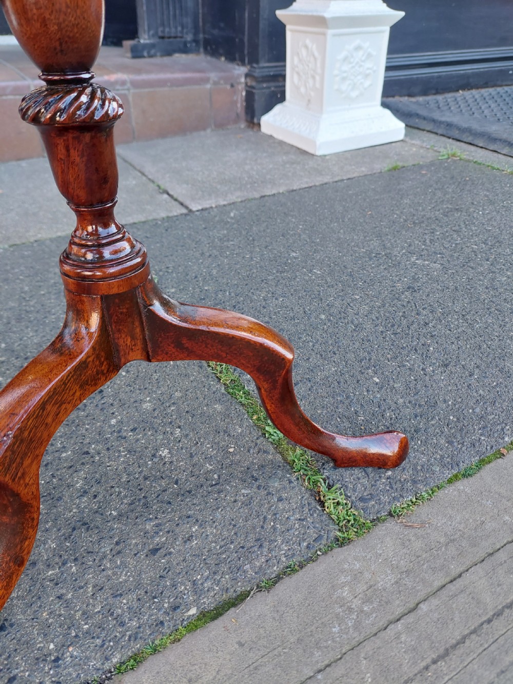 An Edwardian mahogany wine table featuring a polished circular top, turned central column, and three cabriole tripod legs. View VII