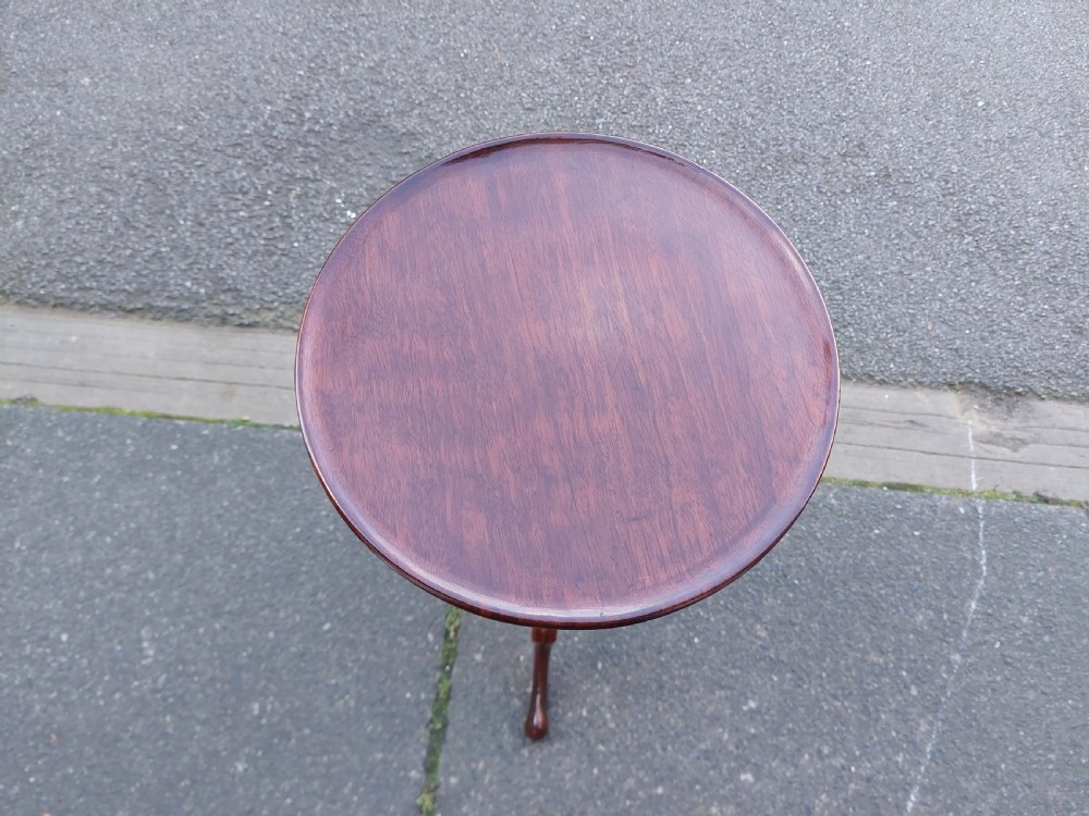 An Edwardian mahogany wine table featuring a polished circular top, turned central column, and three cabriole tripod legs. View IX