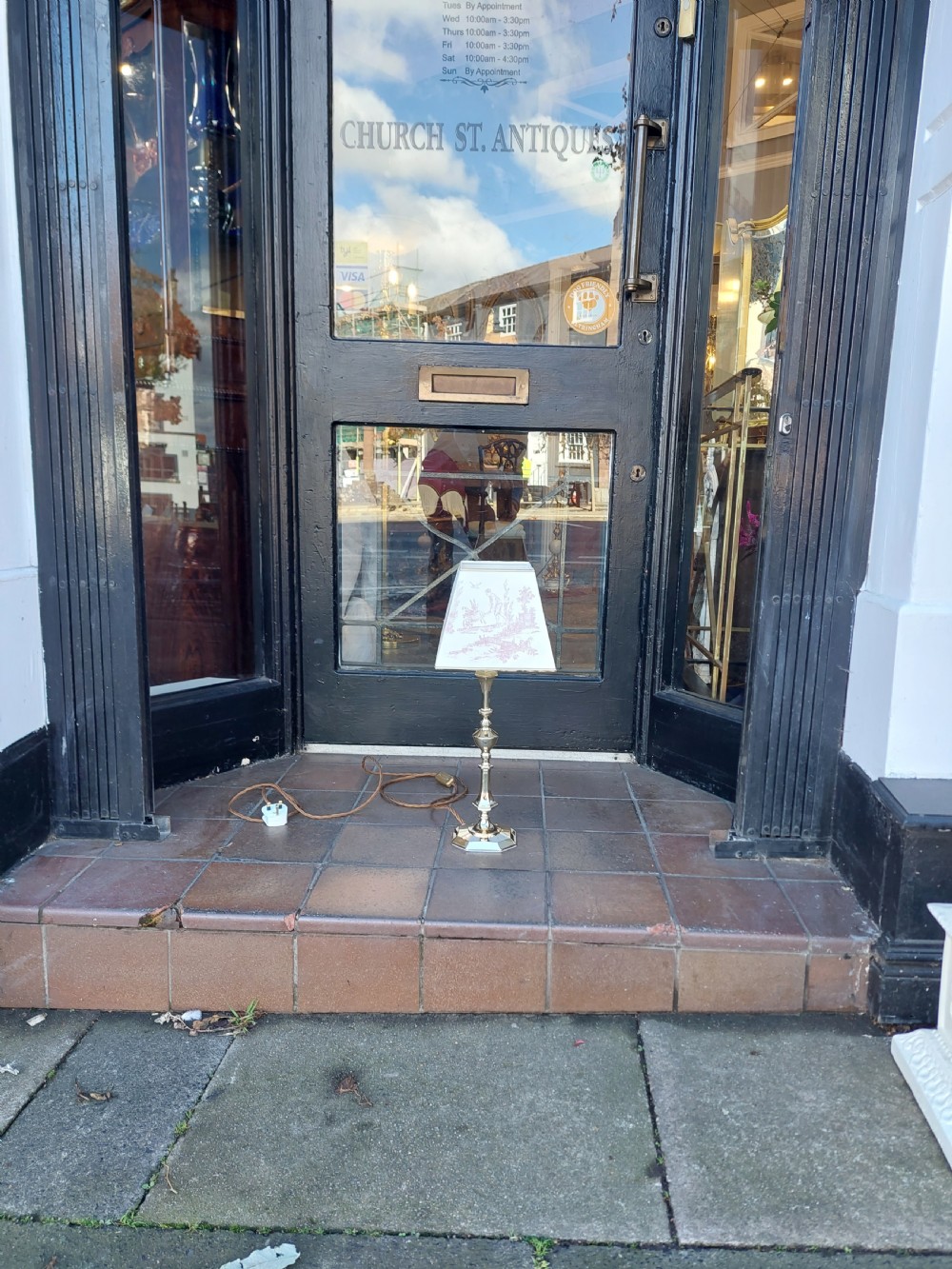 A pair of turned brass Edwardian candlestick table lamps fitted with white pleated lampshades. View VI